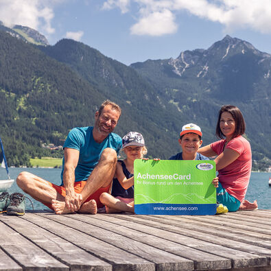 Eine Familie am Steg in Pertisau am Achensee mit der AchenseeCard in der Hand. 