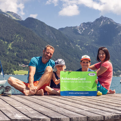Eine Familie am Steg in Pertisau am Achensee mit der AchenseeCard in der Hand. 