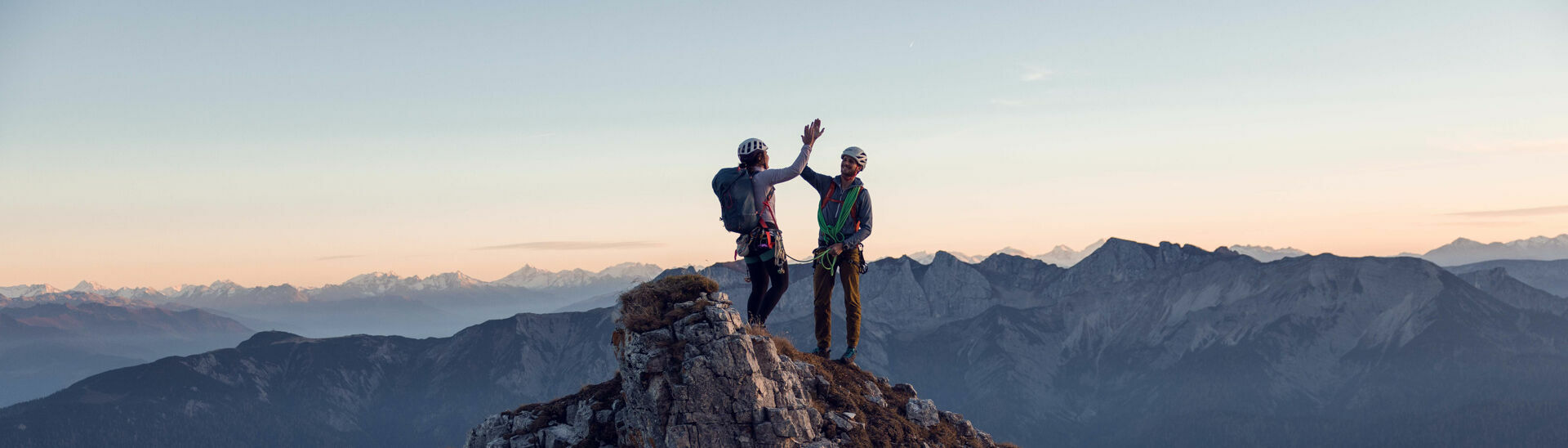 Klettern am Südgrat des Gufferts Zwei Kletterer klatschen miteinander am Gipfel des Gufferts bei leicht gerötetem Himmel ein.