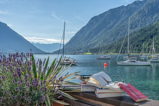 Books from the event "achensee.literatour" specially arranged, backdropped by the spectacular scenery of Lake Achensee, several sailboats and the Ebner Joch.