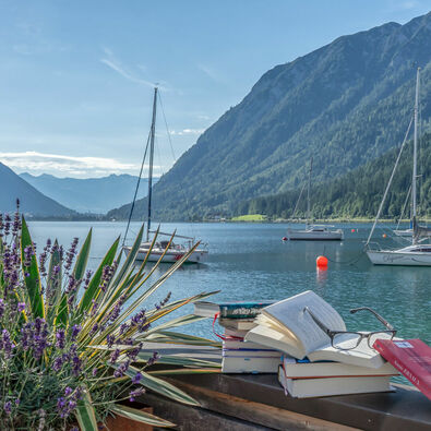 achensee.literatour Im Zuge des Literaturfestivals „achensee.literatour“ wurden viele fesselnde Bücher vor einer atemberaubenden Kulisse in Szene gesetzt, begleitet vom malerischen Achensee, Segelbooten und dem majestätischen Ebner Joch im Hintergrund.