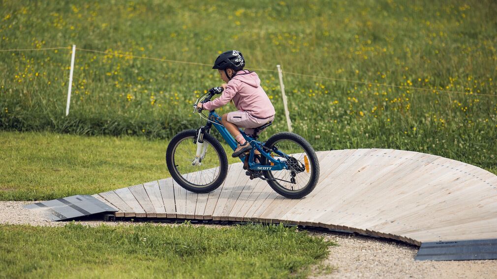 Zwei Kinder trainieren ihre Fahrtechnik am Pumptrack in Achenkirch.