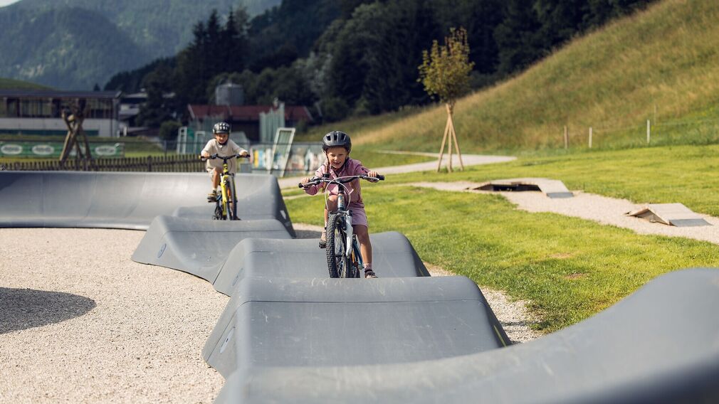 Zwei Kinder trainieren ihre Fahrtechnik am Pumptrack in Achenkirch.